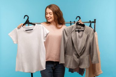 Giysileri askıda tutan, gömleklere bakan, klasik iş ceketi yerine günlük kıyafet seçen, modern butikte alışveriş yapan güzel bir kadın. Stüdyoda çekim izole edildi