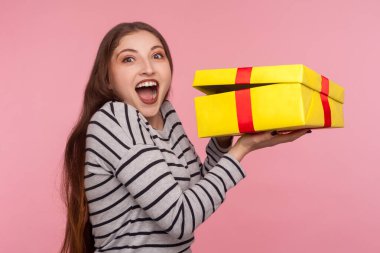 Portrait of happy excited woman in striped sweatshirt looking amazed and screaming joyfully, opening gift box, unpacking best present, birthday surprise. indoor studio shot isolated on pink background clipart