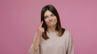 Insane idea! Displeased brunette young woman showing stupid gesture, looking disappointed with senseless dumb suggestion, accusing bad mind, crazy plan. indoor studio shot isolated on pink background