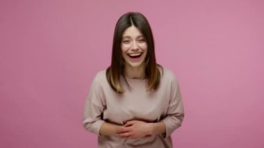 Neşeli esmer, kaygısız genç kadın gerçekten komik bir şakayla eğleniyor karnını tutuyor ve yüksek sesle gülüyor, komik anekdotlarda histerik oluyor. Pembe arka planda kapalı stüdyo çekimleri