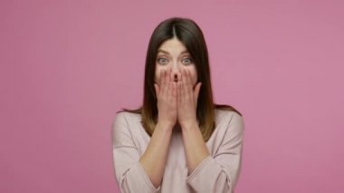 Şaşkınlıkla ağzını açan aşırı heyecanlı esmer kadın, sevinçle bakıyor ve büyük bir başarı karşısında şaşırıyor, zaferle şok oluyor. Pembe arka planda kapalı stüdyo çekimleri