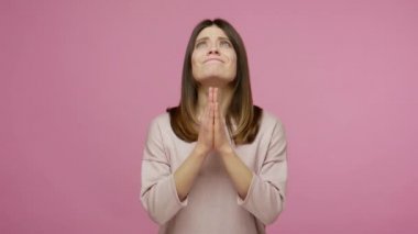 Lütfen, Tanrı 'ya samimi bir yakarış. Esmer genç bir kadın dua ederken el ele tutuşuyor ve yukarı bakıyor, af diliyor, yalvaran gözlerle yardım dileniyor. Pembe arka planda kapalı stüdyo çekimleri