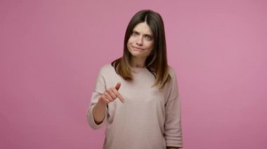 Hemen buraya, bana gel! Patronluk taslayan esmer genç bir kadın kızgın bir ifadeyle işaret ediyor, kontrol etmeyi ve derhal emir vermeyi talep ediyor. Pembe arka planda kapalı stüdyo çekimleri
