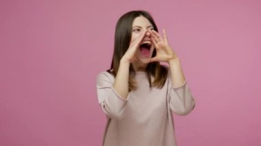 Stressed out, upset brunette woman holding hands around mouth and shouting with loud voice, screaming announcement, pissed off and got rid of aggression. indoor studio shot isolated on pink background