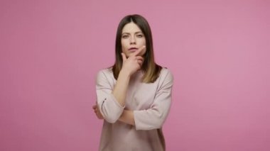 Ciddi sorunları çözerken çenesini ovuşturan düşünceli esmer kadın, onaylayıcı bir şekilde başını sallıyor, zekice bir fikir üzerinde düşünüyor, düşünüp taşınıyor. Pembe arka planda kapalı stüdyo çekimleri
