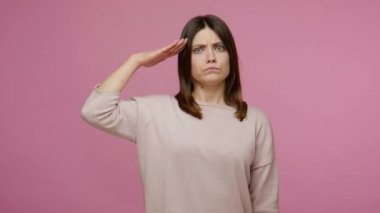 Evet, efendim! Sorumlu esmer bir genç kadın selamlıyor ve onaylıyor, vatansever yüz ve disiplin kavramı ile düzeni dikkatle dinliyor. Pembe arka planda kapalı stüdyo çekimleri