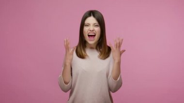 Stres, öfke duyguları. Kızgın esmer kadın bağırıyor, deli gibi bakıyor öfkeyle, öfkeyle ve öfkeyle kavga ederken yumruk sallıyor. Pembe arka planda kapalı stüdyo çekimleri