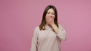 Uykulu, yorgun, esneyen, ağzı eliyle kaplayan uykusuz bir geceden sonra enerji eksikliği, uykusuzluktan kıvranan bir kız. Pembe arka planda kapalı stüdyo çekimleri