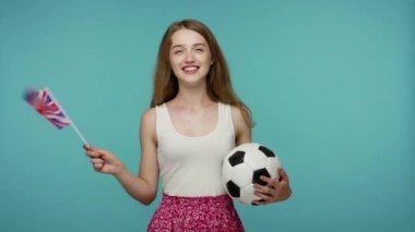 Futbol topu tutan ve İngiliz bayrağı sallayan mutlu güzel kız futbol fanatiği favori spor maçını izliyor, zafer için tezahürat yapıyor, kazanma umuduyla. Stüdyoda çekim izole edildi