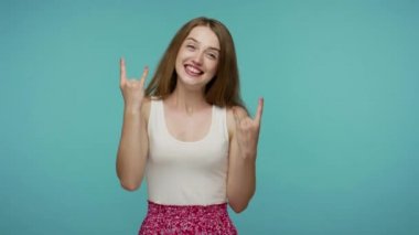 Dertsiz tasasız, güzel bir kızın dil göstermesi ve rock 'n roll el hareketi, punk işareti, galibiyetten dolayı heyecanlı bağırması, başarı için çıldırması. Mavi arka planda kapalı stüdyo çekimleri