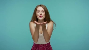 Mutlu, açık yürekli, güzel bir kız herkese güzel öpücükler yolluyor, herkese olumlu duyguları paylaşıyor ve kaygısız bir şekilde gülümsüyor, cömertlik konsepti. Mavi arka planda kapalı stüdyo çekimleri