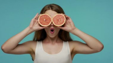 Mutlu iyimser kız gözlerini greyfurtla kapayıp dil gösteriyor, meyvelerle oynarken eğleniyor, vitamin yemeğinin, sağlıklı beslenmenin ve vejetaryen yaşam tarzının tadını çıkarıyor. Stüdyo çekimi izole