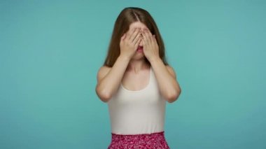 Hayır, bunu görmek istemiyorum! Korkmuş üzgün kız elleriyle yüzünü ve gözlerini kapatıyor, korkudan saklanıyor, iğrenç içeriği izlemeyi reddediyor, utanç verici bir şey. Mavi arka planda kapalı stüdyo çekimleri
