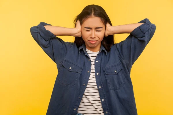 我不想听 穿着粗斜纹棉布衬衫的生气女孩的画像 被讨厌的噪音 嘈杂的声音 难以听清的高音烦扰着耳朵 在黄色背景下隔离的室内拍摄 — 图库照片