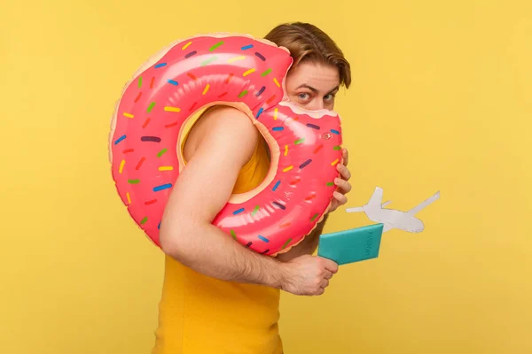 Pembe Donut Kauçuk Halkasının Arkasına Saklanan Elinde Pasaport Uçak Maketi — Stok fotoğraf