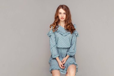 Kıvırcık esmer saçlı, eski püskü elbiseli, sakin bir ifadeyle kameraya bakan güzel bir kızın portresi. Moda modası, güzellik konsepti. Stüdyoda çekim izole edildi