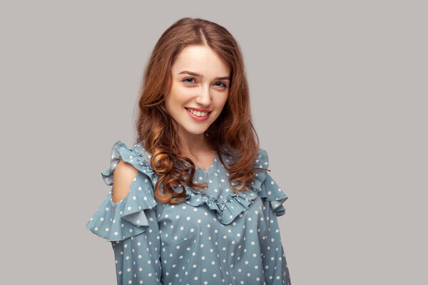 Счастливая брюнетка, глядящая на камеру с зубастой улыбкой, гламурная модель с естественным блеском чистой кожи, красота и мода. студия съемки изолированы на сером фоне
