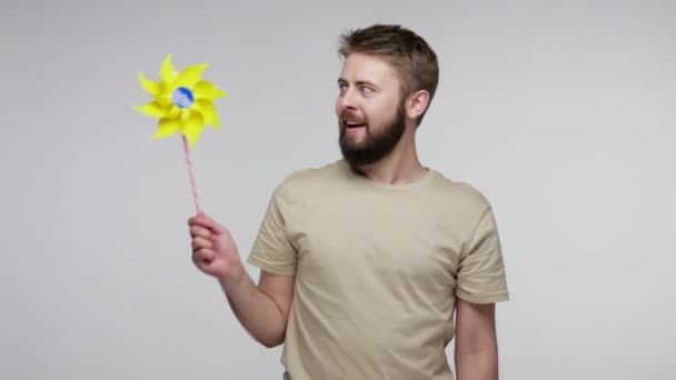 Happy Young Bearded Guy Playing Origami Pinwheel Blowing Toy Windmill — Stock Video