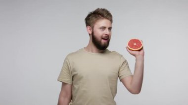 Greyfurt ve küçük pembe dambıl gösteren pozitif sakallı adam, diyet vitamini beslenme, fitness eğitimi, sağlıklı sportif yaşam tarzı sağlıyor. Gri arka planda kapalı stüdyo çekimi