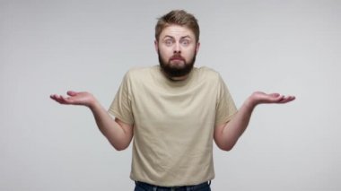 Bilmiyorum, üzgünüm! Utangaç sakallı adam omuz silkiyor, kafası karışık belirsiz bir ifadeyle bakıyor, şüpheleri var, tereddütleri var. Gri arka planda kapalı stüdyo çekimi