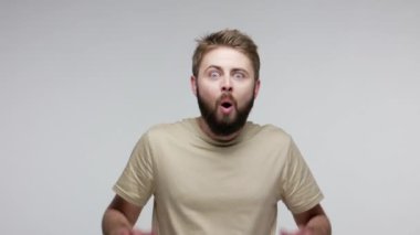 Vay canına, inanılmaz! Sakallı adam şok olmuş bir ifadeyle el kaldırıyor, kameraya şaşırmış büyük gözlere bakıyor, ağzı açık şaşkınlık, inançsızlık ve mutlu bir tepki gösteriyor. Stüdyo çekimi izole