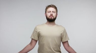 Sakallı serbest çalışan bir erkek ya da öğrenci, günlük tişörtler içinde yoga tekniği uyguluyor stresi azaltıyor, dua jestinde el kaldırıyor, düşüncelerini konsantre etmek için meditasyon yapıyor. Stüdyoda çekim izole edildi
