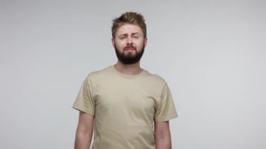 Sıkıcı mutsuz adam kameraya bakıyor kasvetli kasvetli, eli kolu bağlı sıkıcı konuşmaları dinliyor ilgisiz duygular, tembellik ve enerji eksikliği. Gri arka planda kapalı stüdyo çekimi