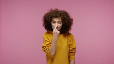 Yalan söylüyorsun! Kapüşonlu kız saçı şüpheli görünüyor, burnuna dokunuyor yalancı jestler yapıyor ve kamerayı işaret ediyor, yalan kavramına güvenmiyor. Stüdyo çekimi pembe arkaplanda izole edildi