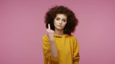 - Geri çekil! Kapüşonlu, huysuz bir kız saçı. Orta parmağını kameraya gösteriyor. Kincilere saygısızlık ve olumsuzluğu ifade ediyor. Pembe arka planda kapalı stüdyo çekimleri