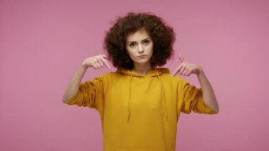 Burada ve şimdi! Kapüşonlu, otoriter bakışlı, sinirli, sert, afro saçlı bir kız. İlişkileri kontrol etmeyi talep ediyor. Pembe arka planda kapalı stüdyo çekimleri