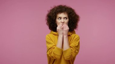 Kapüşonlu, tırnaklarını yiyen, güvensiz, korkmuş afro saçlı bir kız ciddi sorunlar, stres bozukluğu ve anksiyete bozukluğu konsepti hakkında endişeli. Pembe arka planda kapalı stüdyo çekimleri