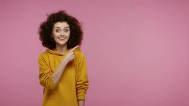 Vay canına, reklama bak! Kapüşonlu, fotokopi odasını gösteren afro saçlı mutlu bir kız. Promosyon metni ve pazarlama için boş bir duvar gösteriyor. Pembe arka planda kapalı stüdyo çekimleri