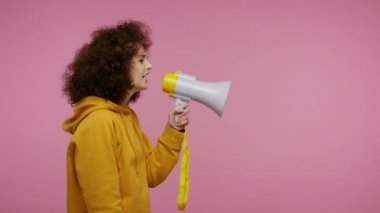 Yan görüş, kapüşonlu kız saç stili megafonla konuşuyor, haberleri duyuruyor, yüksek sesle reklam veriyor, hoparlörü kullanarak konuşma için uyarıda bulunuyor. Stüdyo çekimi pembe arkaplanda izole edildi