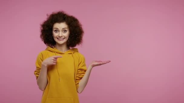 Menina Incrível Afro Penteado Com Capuz Apontando Lugar Vazio Palma — Vídeo de Stock