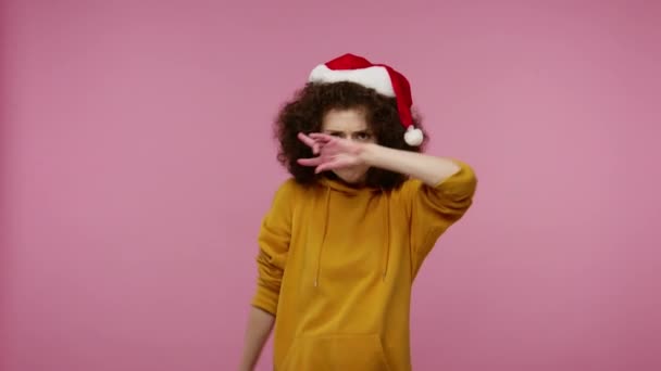 滑稽而积极的女孩带着圣诞老人的帽子跳舞唱歌 感到无忧无虑的快乐 精力充沛地跳舞 在圣诞晚会上放松 在粉色背景上隔离的工作室拍摄 — 图库视频影像