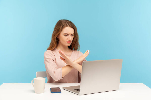 Запретная служба! Злая строгая деловая женщина, скрещивающая руки, показывающая знак x, останавливающая жесты во время видеозвонка, глядя на экран ноутбука с негативным предупреждением. закрытая студия
