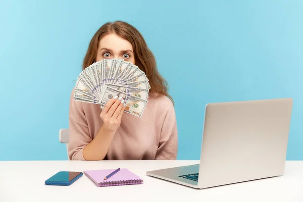 面白い驚きの女性従業員は ラップトップで職場に座って ドル紙幣を見て 驚きの大きな目で見て 高い給与にショックを受けた 屋内スタジオで孤立した青の背景を — ストック写真