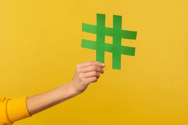 Internet trends, famous network content. Closeup of hand holding hashtag sign, sharing tagged message, popular idea, blogging and viral web post. indoor studio shot isolated on yellow background