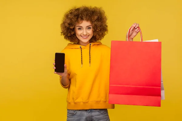 Retrato Menina Hipster Encaracolado Otimista Capuz Segurando Celular Sacos Compras — Fotografia de Stock