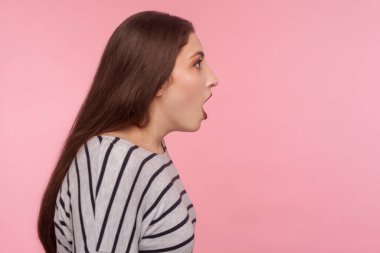 Aman Tanrım, vay canına! Çizgili tişörtlü, ağzı açık duran, hayretler içinde, inanılmaz şok edici habere şaşırmış bir kadının yan görüntüsü. Stüdyo çekimi pembe arkaplanda izole edildi