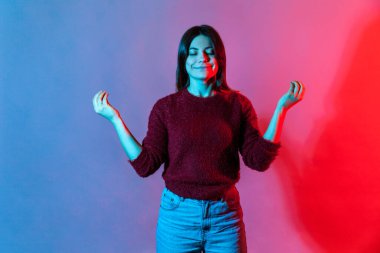 Huzur ve rahatla, konsantre zihin. Neon ışığı portresi, sakin, güzel bir kadının Mudra jesti ile el ele tutuşması, meditasyon yaparken gözlerini kapalı tutması, yoga çalışması. Stüdyoda çekim izole edildi