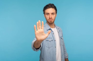 İçki yasağı, giriş izni yok. İşçi kot gömleği giyen ciddi bir adamın, avuç içi ile dur işareti yapan, olumsuz jestli uyarı ifadesi yapan portresi. Mavi arka planda kapalı stüdyo çekimleri