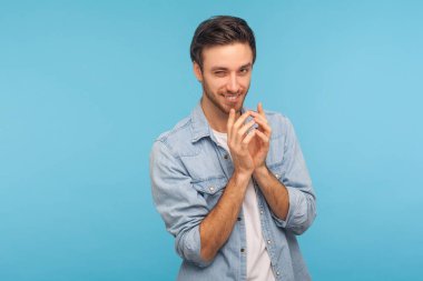 Kurnaz hilekar, işçi kot gömleği giyen sinsi bir adam sinsi bir intikam planı, entrika ve komplo kuran kötü adam portresi. Stüdyo çekimi mavi arkaplanda izole edildi