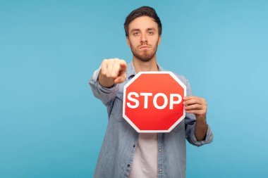Hey sen, giriş yasak! İşçi kot gömleği giymiş otoriter bir adamın portresi kamerayı işaret ediyor ve yasaklama ve yasaklama sembolü olarak trafik işaretini tutuyor. Stüdyoda çekim izole edildi