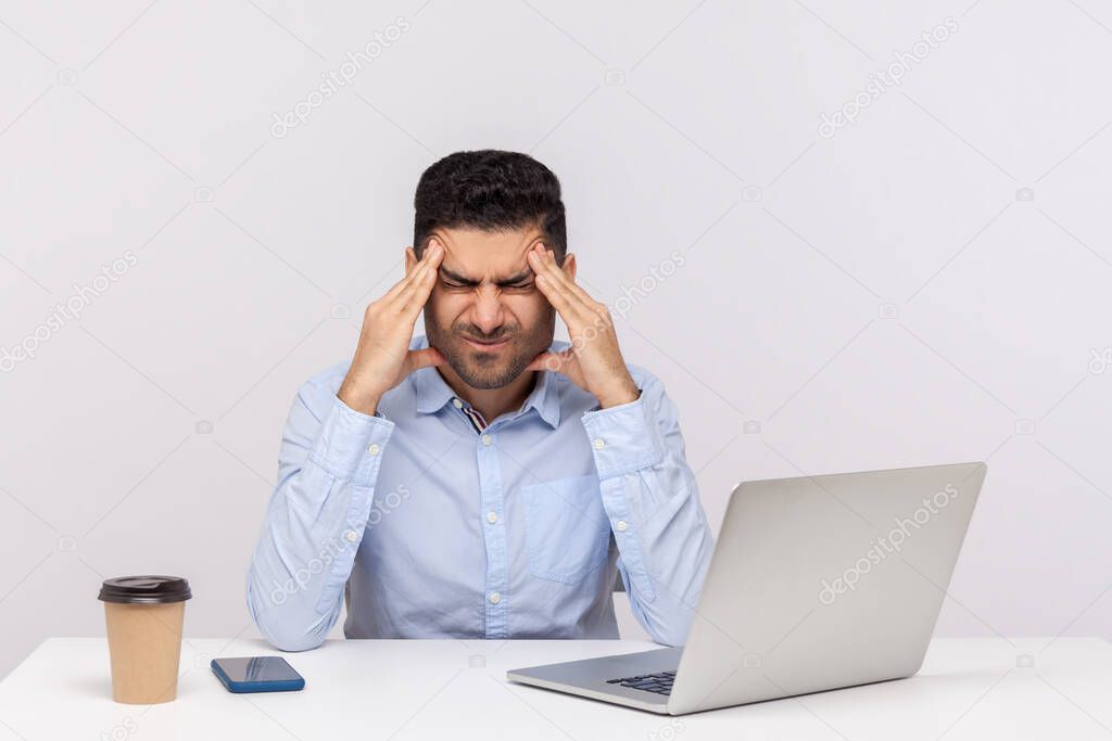 Unhealthy tired businessman sitting office workplace, clasping painful head, suffering severe migraine of overwork and stressful job, worried about troubles. studio shot isolated on white background