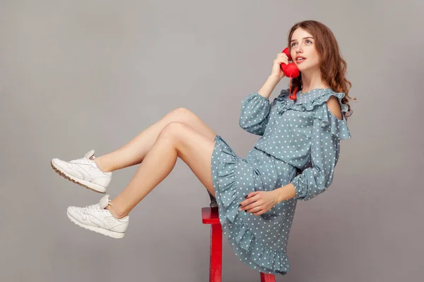 드레스를 매력적 소녀가 의자에 공기를 마시고 전화로 즐거운 대화를 나누면서 — 스톡 사진