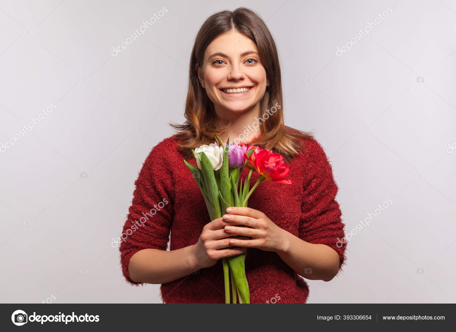 迷人而快乐的黑发女郎的画像捧着花束带着灿烂的微笑看着相机春天的心情祝贺3月8日妇女日在灰色背景下隔离的工作室拍摄