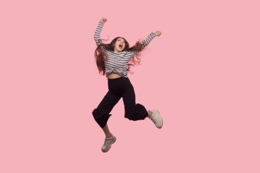 Yaşam enerjisi, zafer. Coşkulu, son derece mutlu, sevinç ve uçmak için bağıran, yumruklarıyla havaya atlayan, başarıyı kutlayan bir kadının portresi. Stüdyo çekimi izole, tam uzunlukta