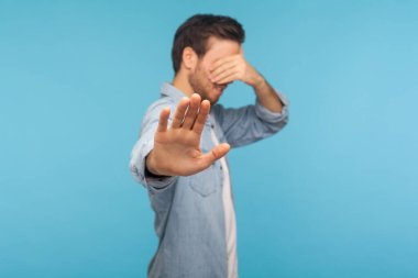 - Hayır, izlemek istemiyorum! İşçi kot gömleği içinde utangaç bir adamın portresi gözlerini kapatıyor. Durma hareketi gösteriyor. Utanç verici içeriğe bakmayı reddediyor. İç mekan stüdyo çekimi, mavi arka plan