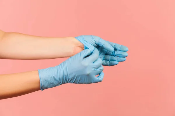 手袋の取り方を示す青い外科用手袋で人間の手のプロフィール側のビューを閉じます ピンクの背景に隔離された屋内スタジオでの撮影 — ストック写真